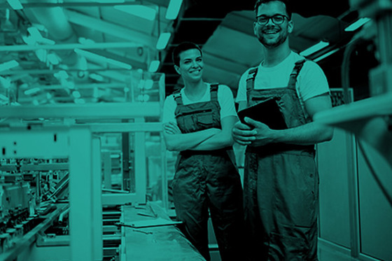 Two workers in a factory, smiling to the camera