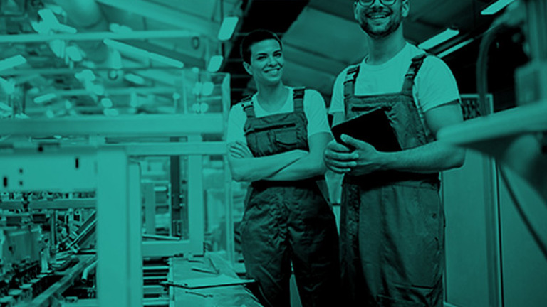Two workers in a factory, smiling to the camera