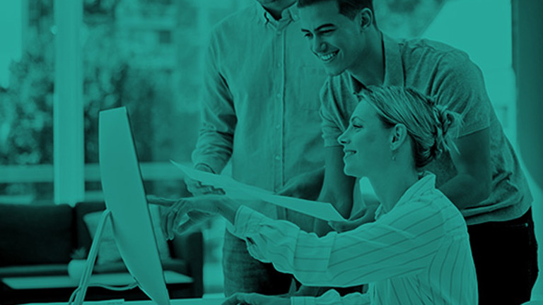 Three people by a desk looking at a computer