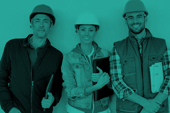 Three people with safety helmets, smiling at the camera