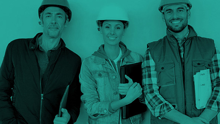 Three people with safety helmets, smiling at the camera
