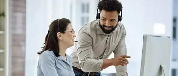 Two customer care people looking at screen