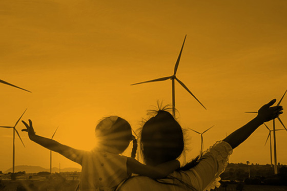 Silhouette of adult and child against a backdrop of landscape with wind turbines
