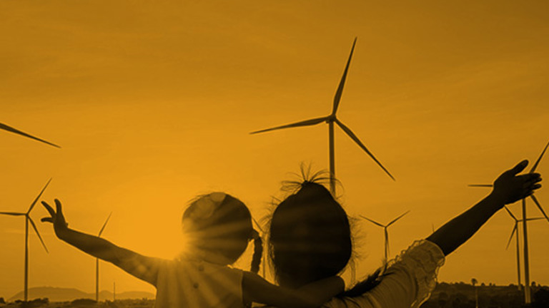 Silhouette of adult and child against a backdrop of landscape with wind turbines